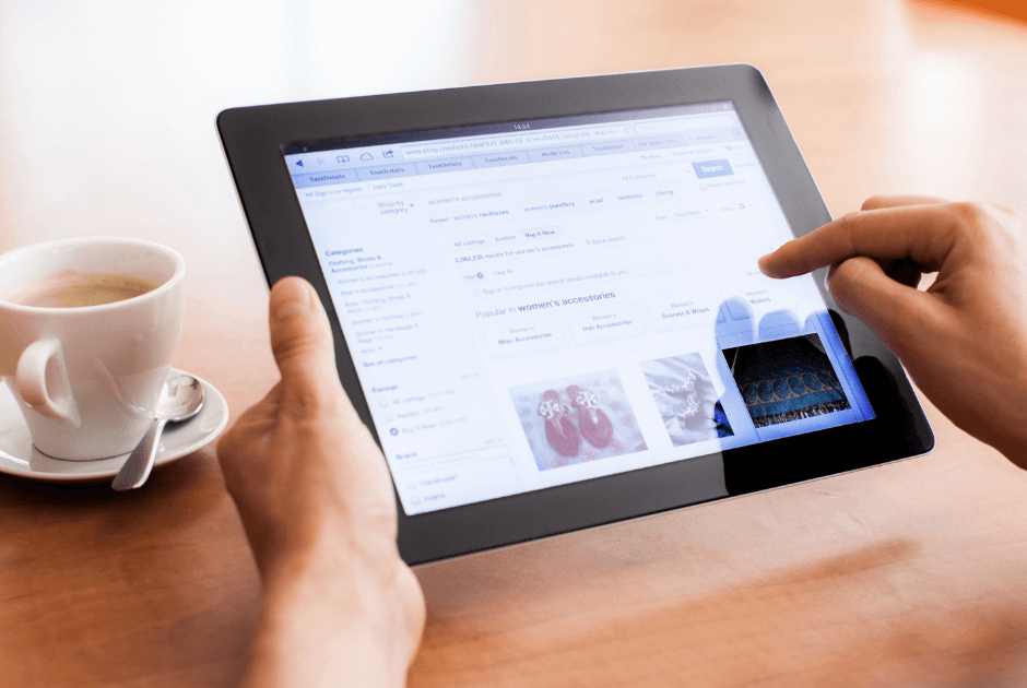 A person holding a tablet beside a cup of coffee