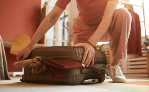 A woman trying to close her luggage