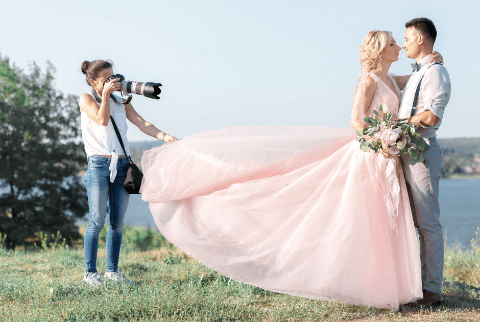 A photographer holding the bride's gown while taking a picture