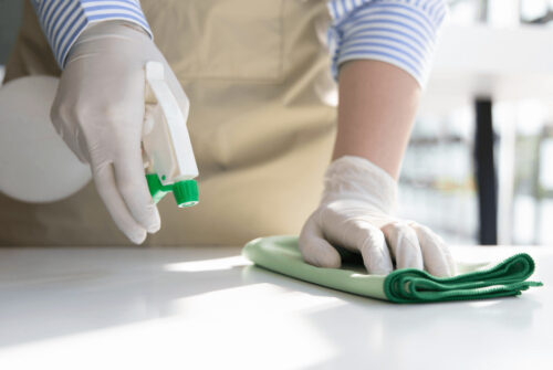 Close-up of hand using spray bottle and towel