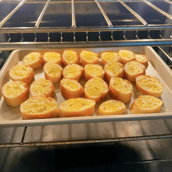 A pan of sliced bread with olive oil inside an oven