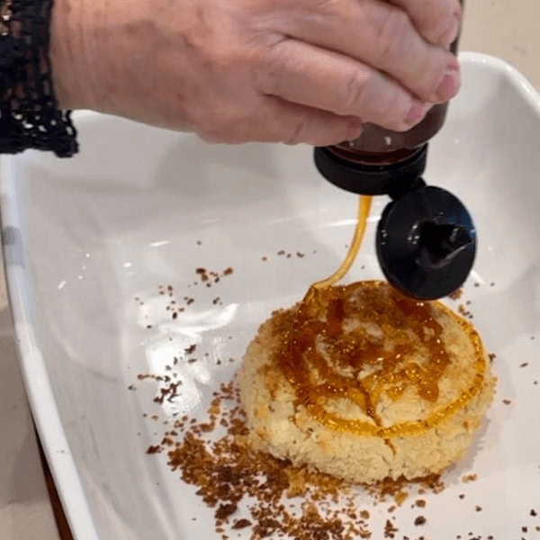 Lori adding hot honey on top of the Crispy Baked Boursin Cheese