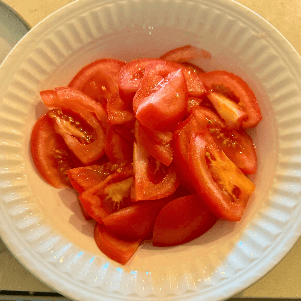 Marinated sliced tomatoes in a white bowl