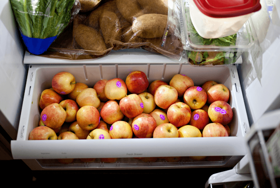 A drawer full of apples in a fridge