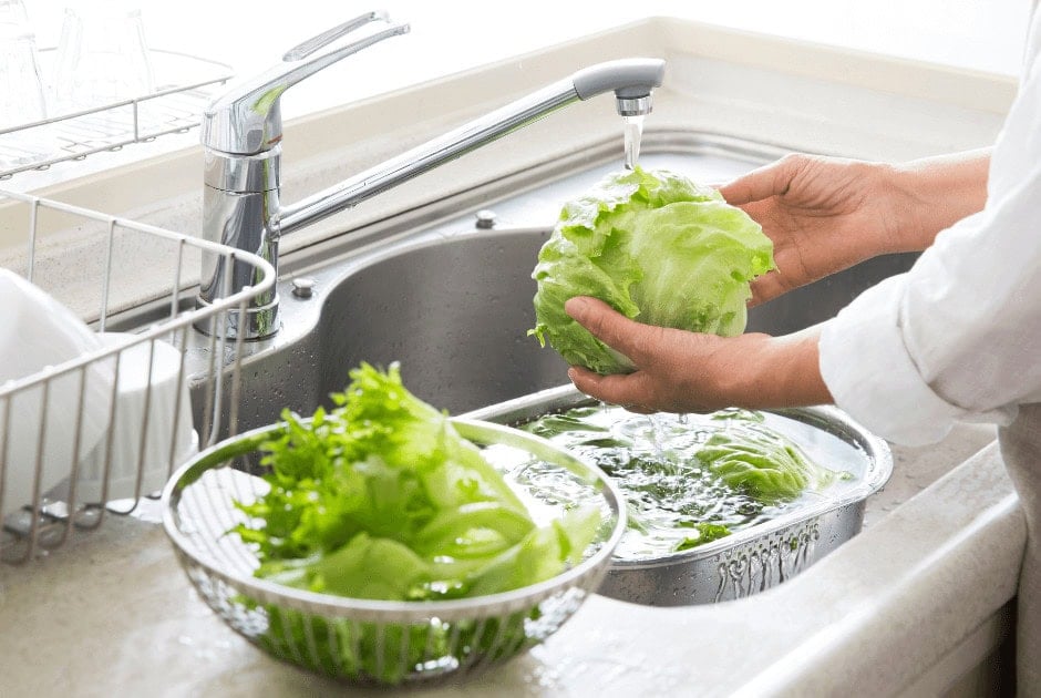 A person washing salad greens