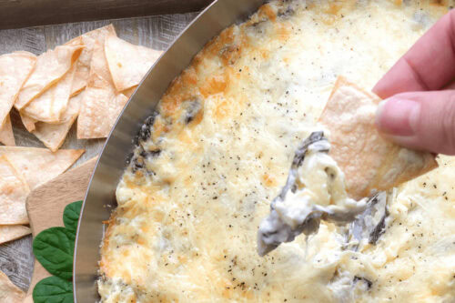 A tortilla dipped into Cheesy Spinach Artichoke Dip