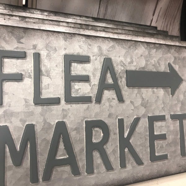 an old tin sign that says Flea Market with an arrow